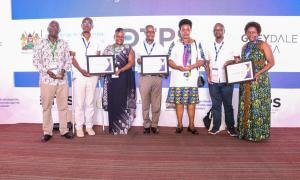Director General of Immigration, Evelyn Cheluget, and team proudly raise their awards for Best Collaborative Digital Public Sector Initiative (ETA), State Department of the Year in Digital Innovation, and 1st Runner-Up in Overall Digital Transformation.